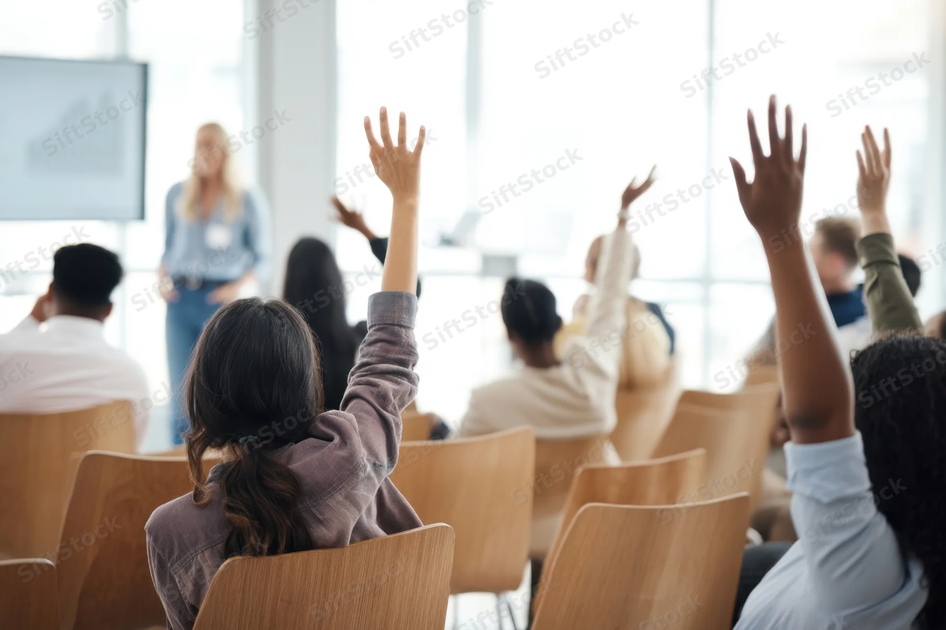 Audience raising hands during presentation in conference room