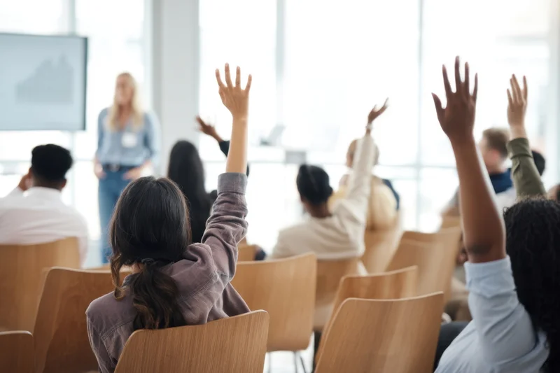 Audience raising hands during presentation in conference room