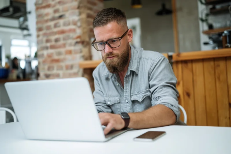 Man working on laptop at white desk in modern office space