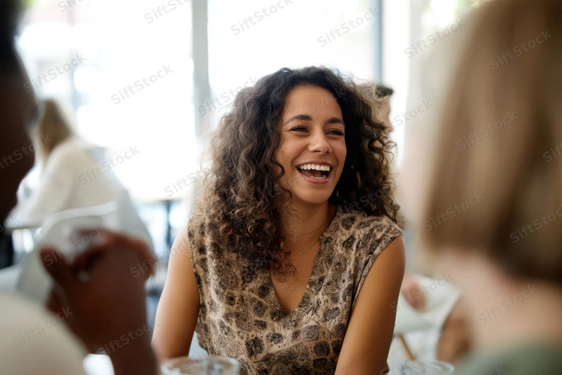 Woman laughing while seated at a cafe table with friends