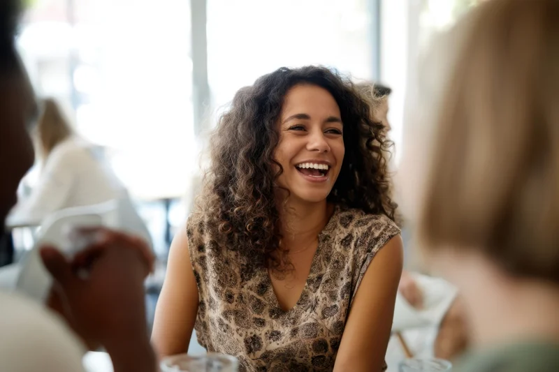Woman laughing while seated at a cafe table with friends