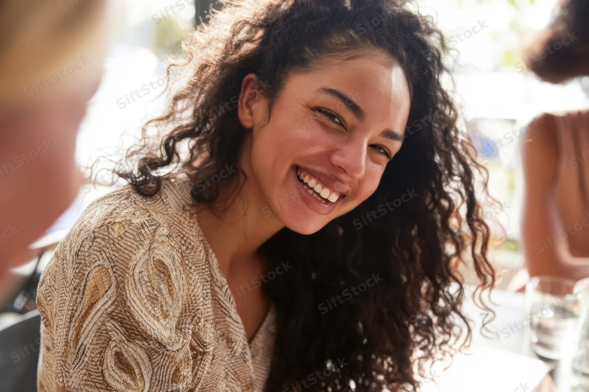 Young black woman smiling at cafe table with friends during daytime social gathering