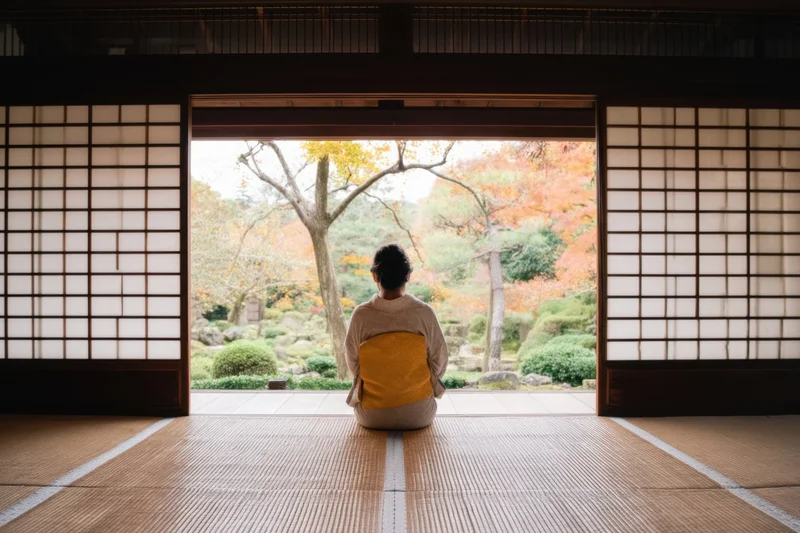Woman in kimono kneeling on tatami facing autumn garden through shoji doors