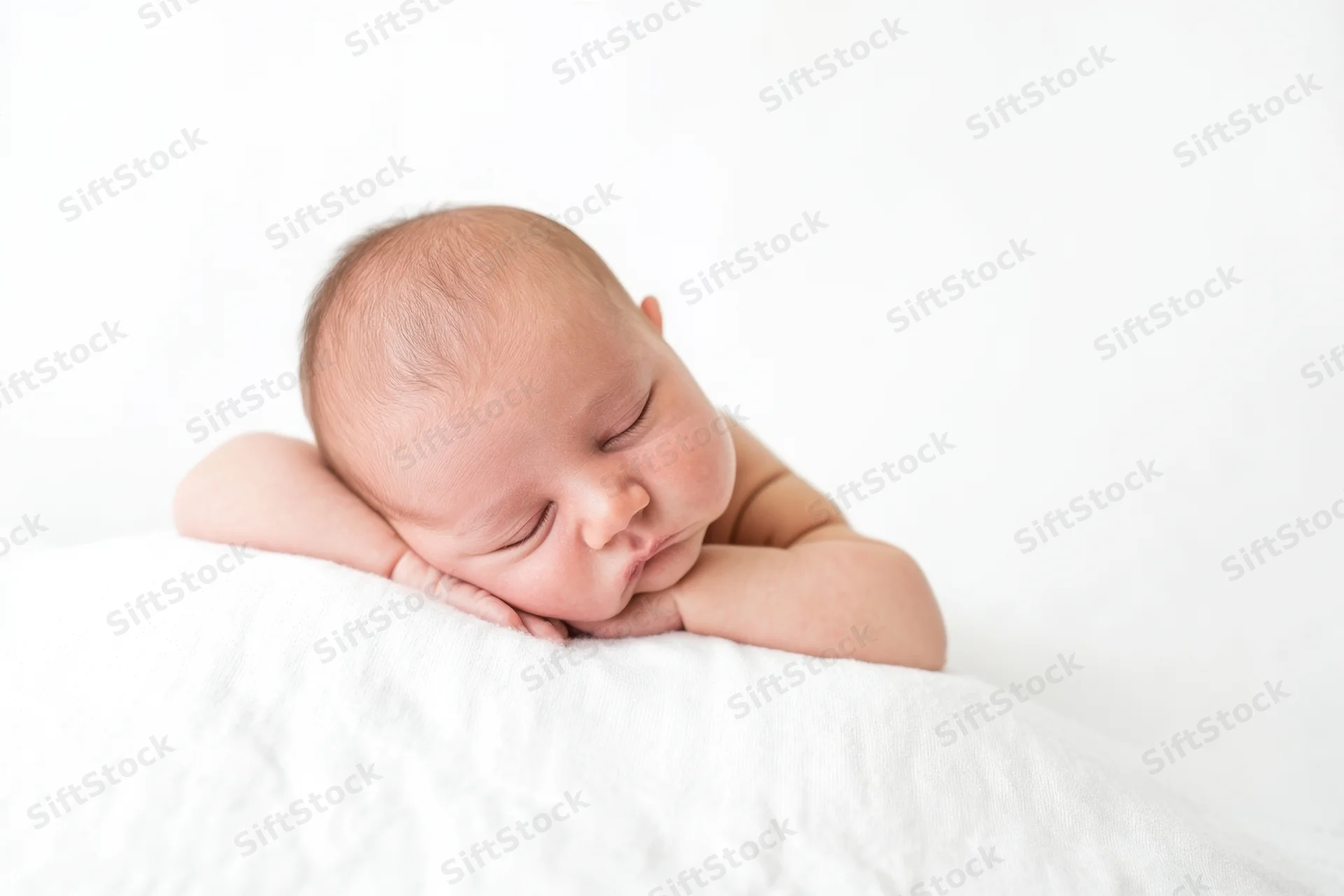 Newborn baby sleeping peacefully on a soft white blanket