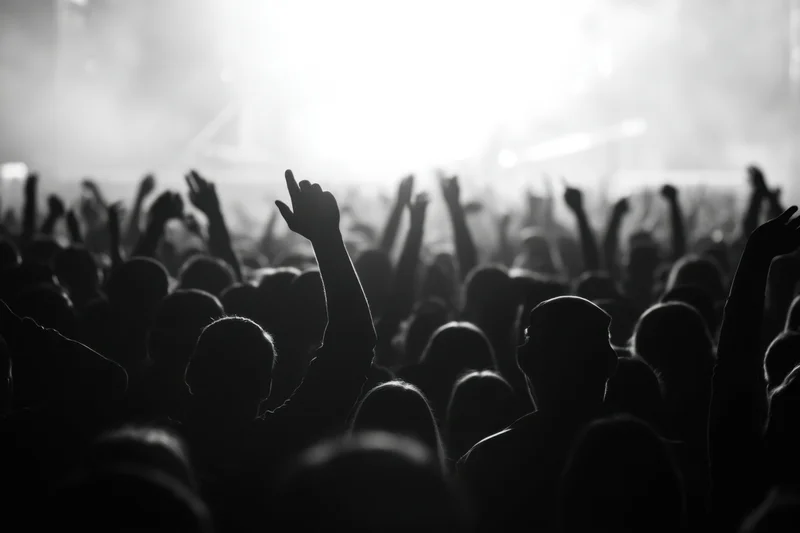 Silhouetted crowd at concert raising hands toward stage lights