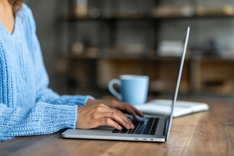 Woman typing on laptop at wooden desk in home office