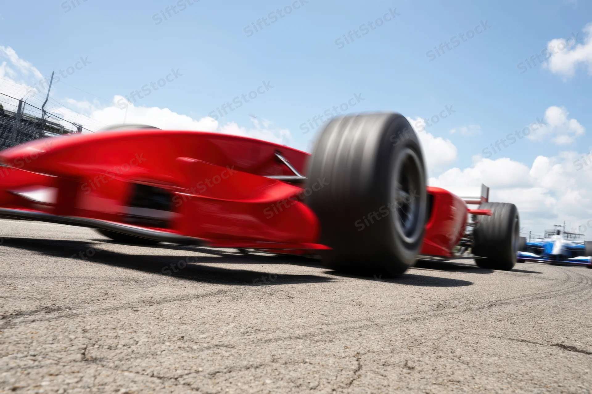 Red formula1 racecar speeding on track from low close angle