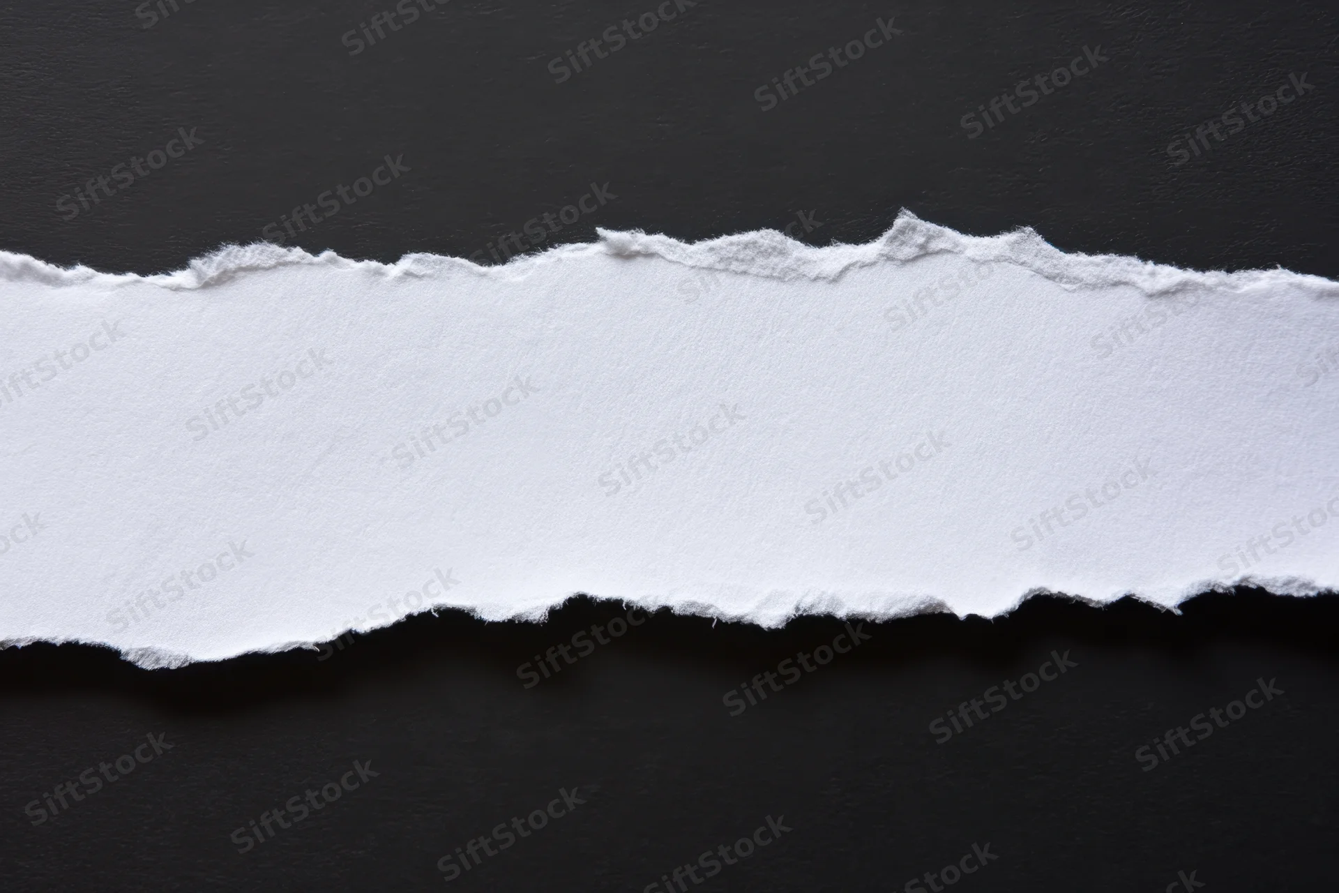 Horizontal torn white paper strip on black background with copyspace