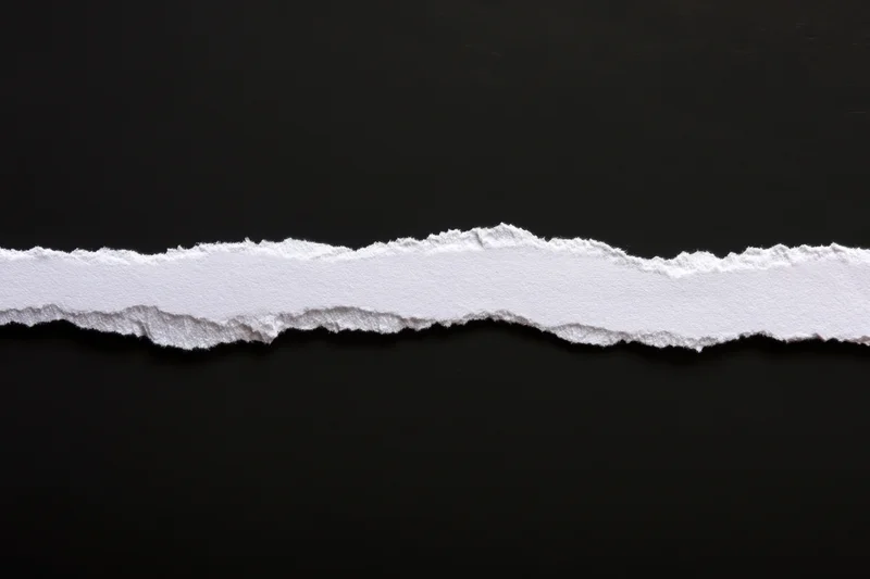 Horizontal torn white paper strip on black background