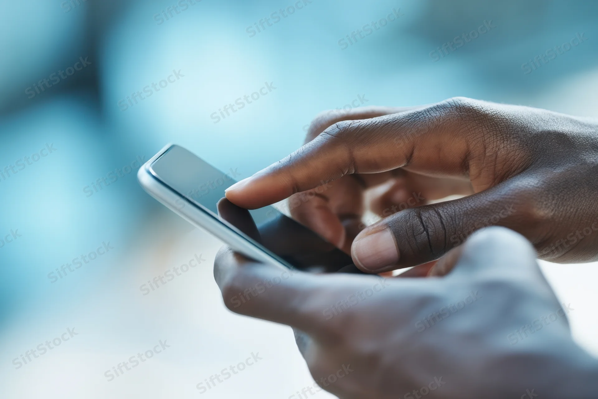 Close-up of dark-skinned hands holding a slim smartphone with finger poised to tap the screen