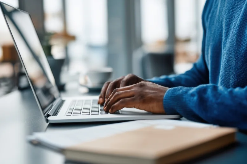 Man typing on laptop at desk in office workspace