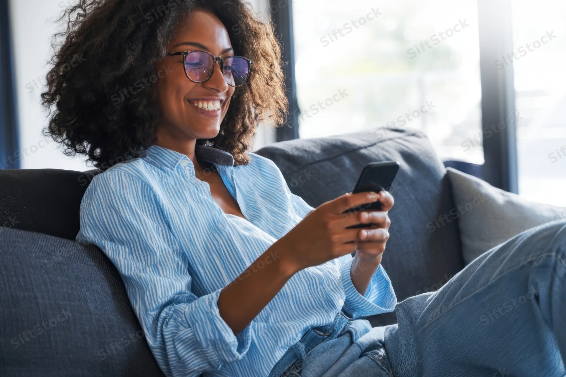 Young woman smiling while using smartphone on couch at home