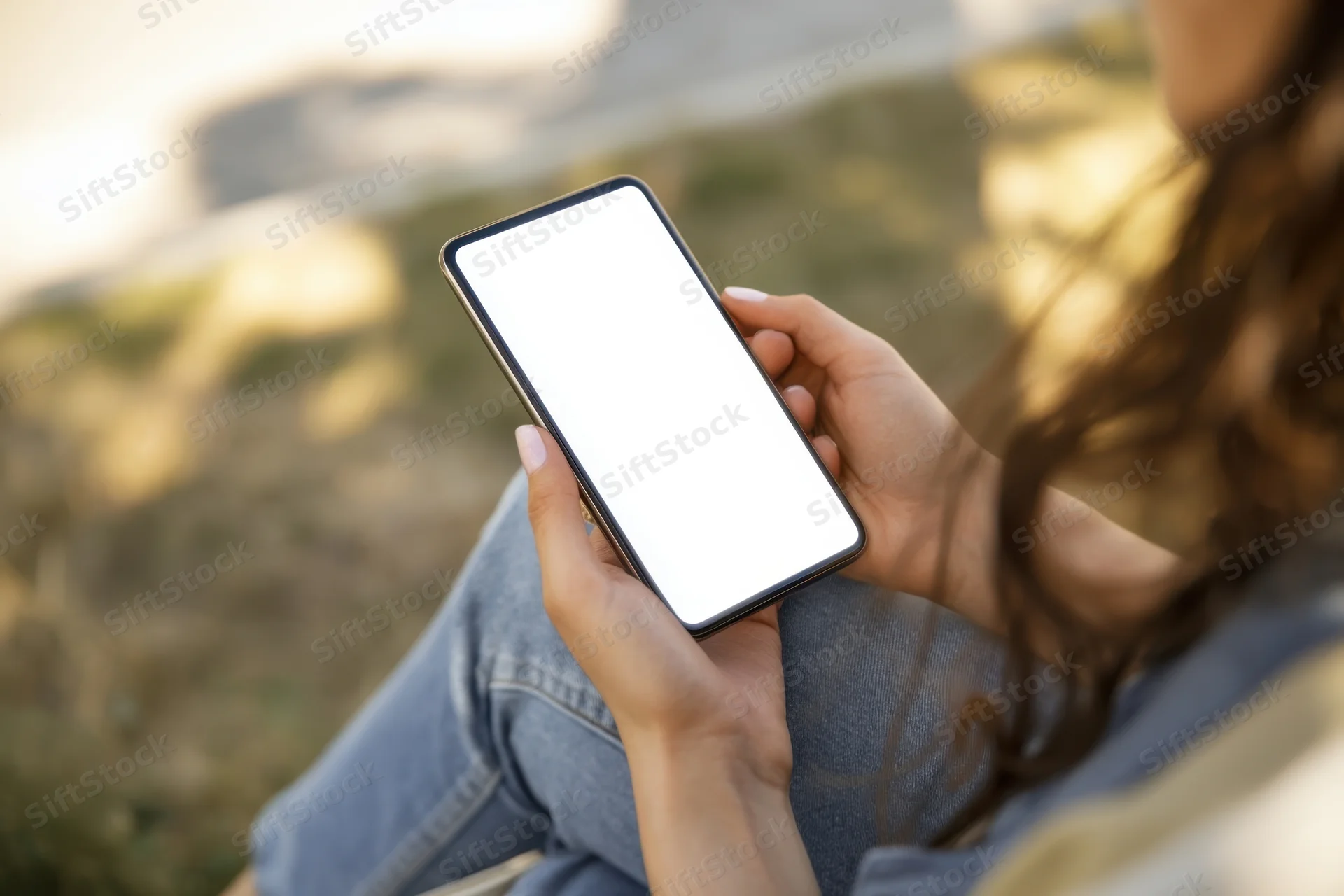 Woman holding smartphone with blank white screen outdoors in park