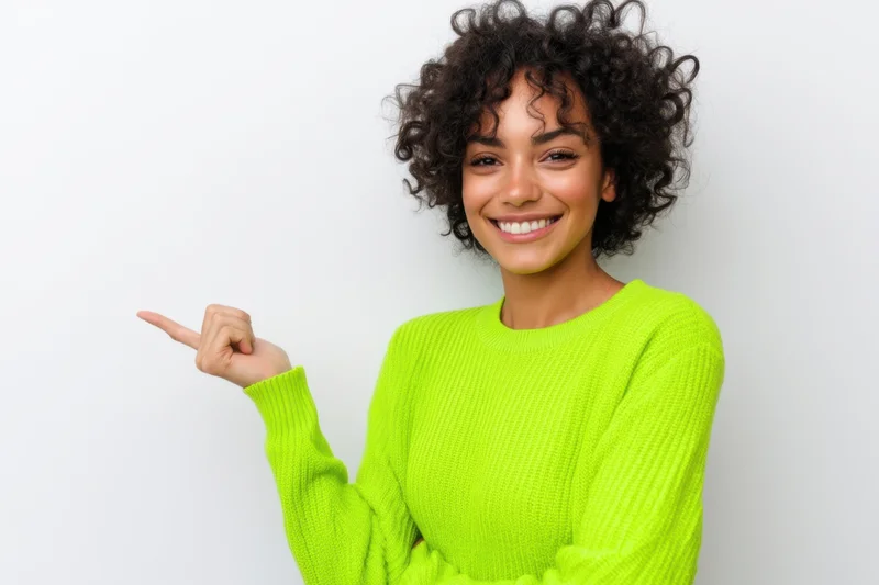 Smiling woman in lime green sweater pointing to the side against white background
