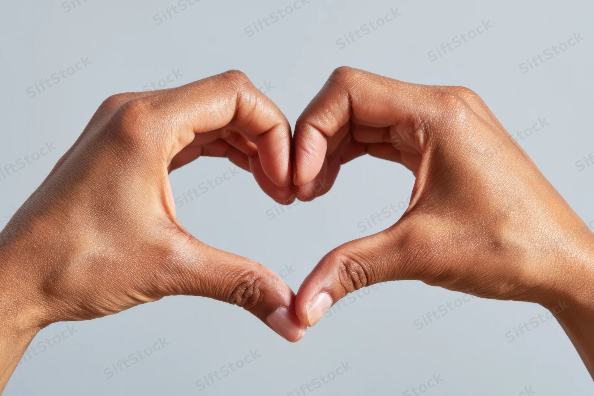 Two hands forming a heart shape against a plain light background