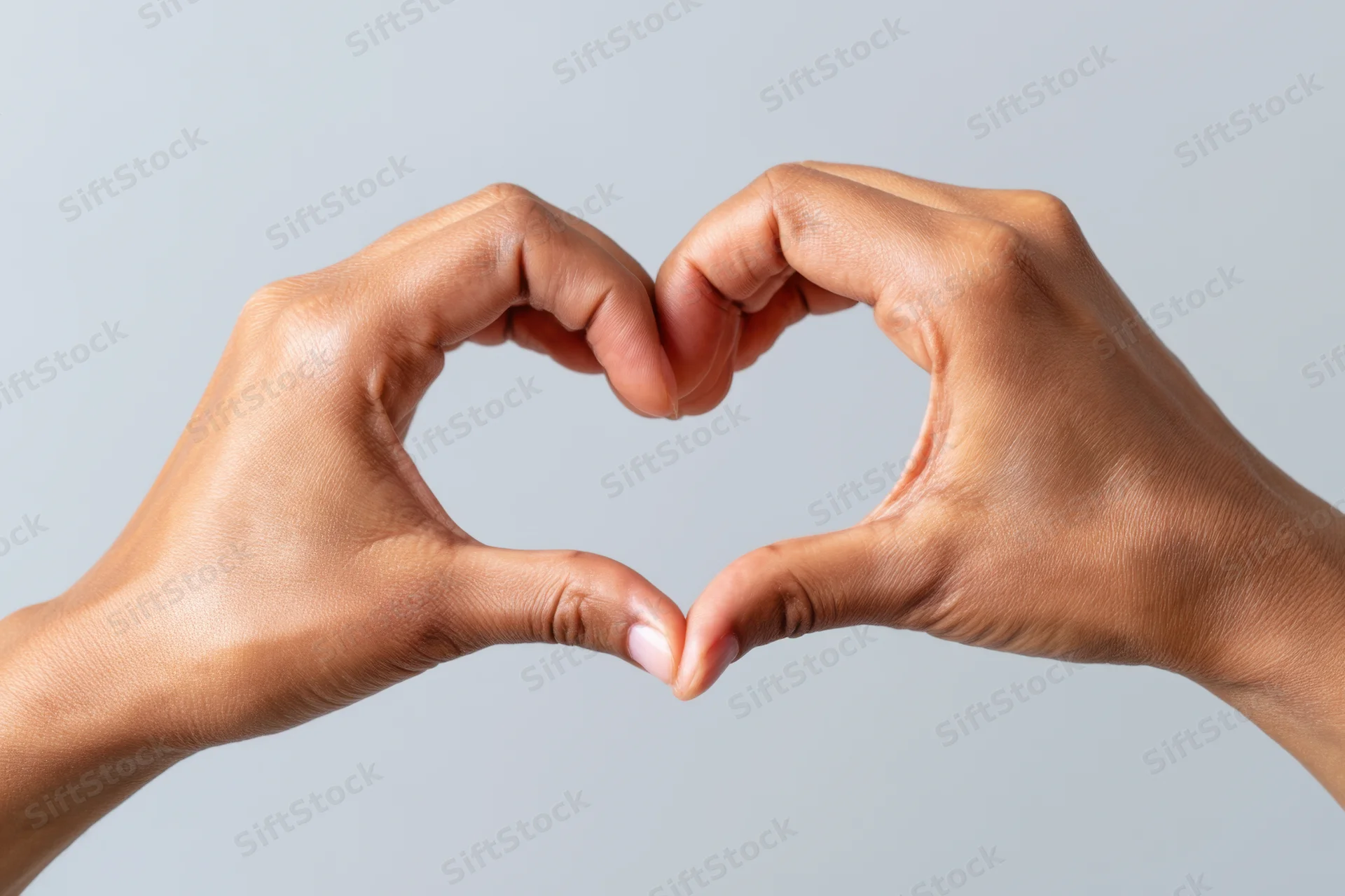 Two hands forming a heart shape against a plain light gray background