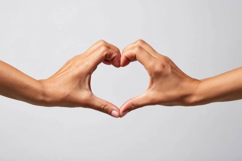 Two hands forming a heart shape against a plain light background