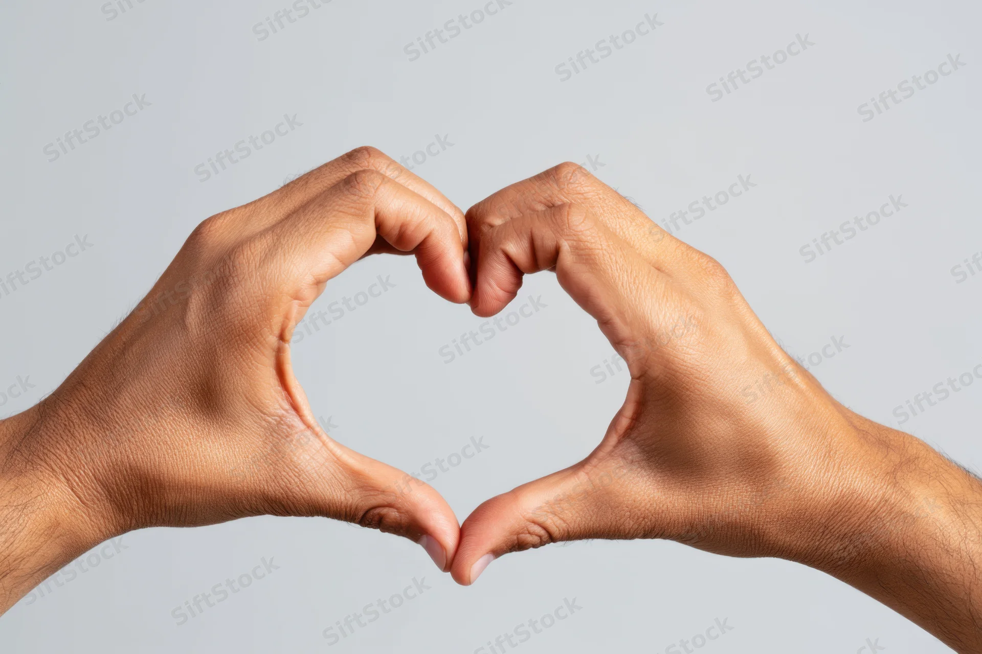 Two hands forming a heart shape against a plain gray background