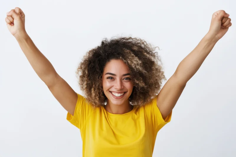 Cheerful woman raising arms in celebration against white background