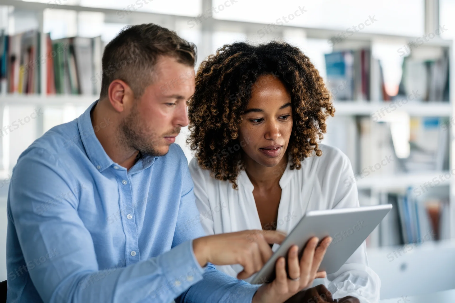 Man and woman collaborating on a tablet in an office setting