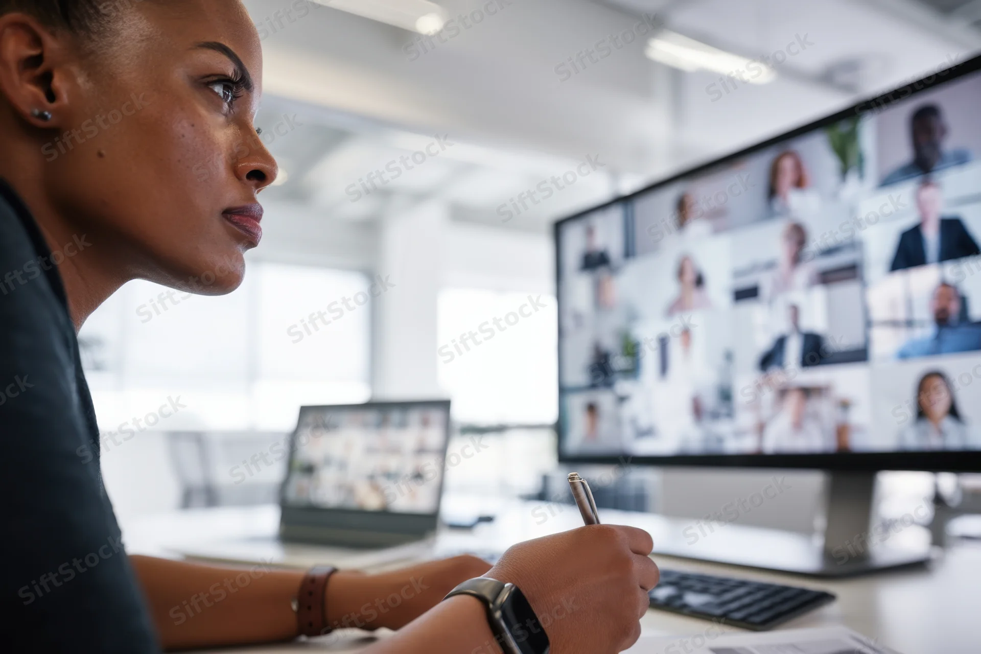 Woman in side profile focused on video conference screen in modern office