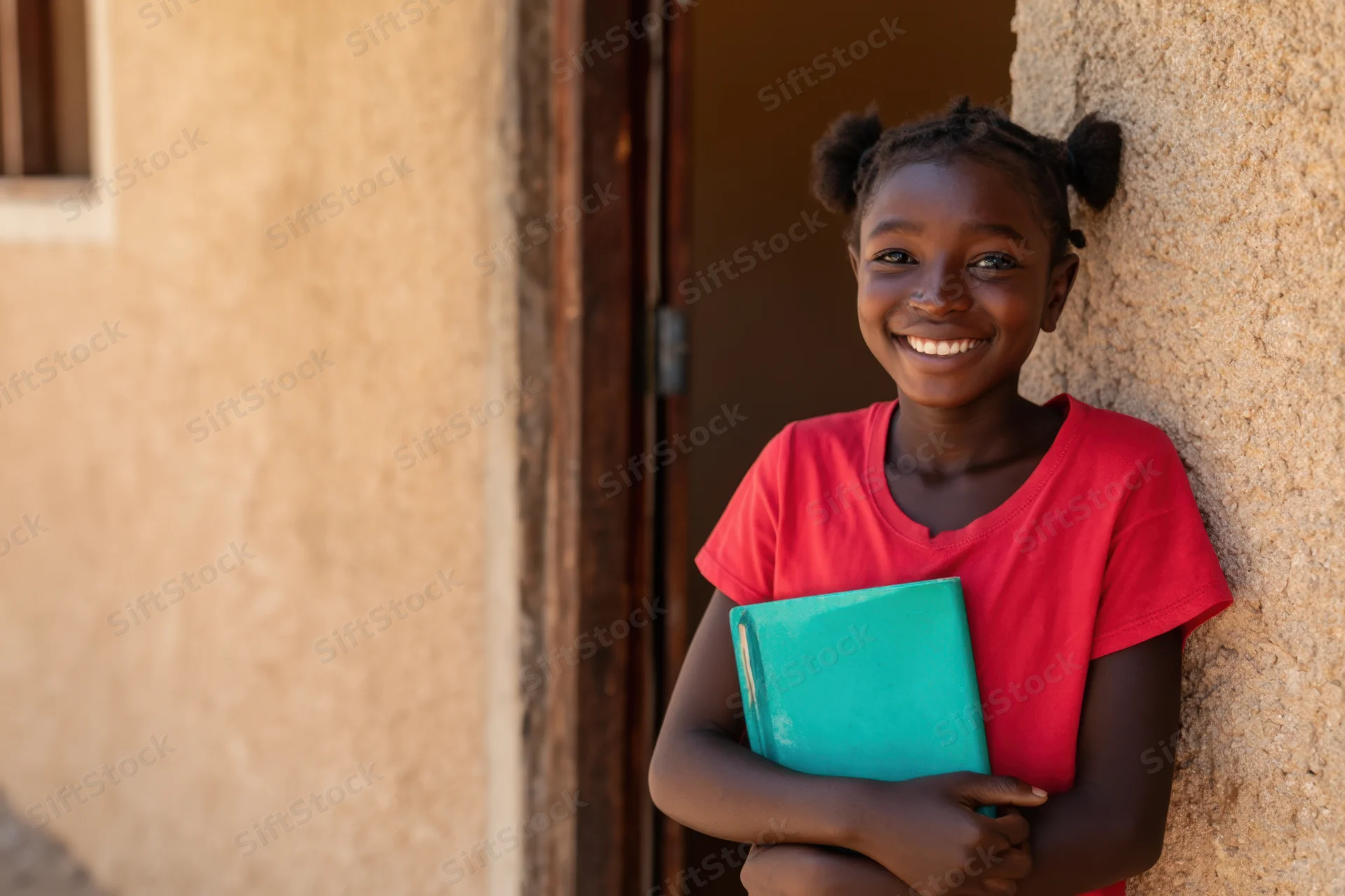 Girl smiling while holding a notebook outside a building doorway