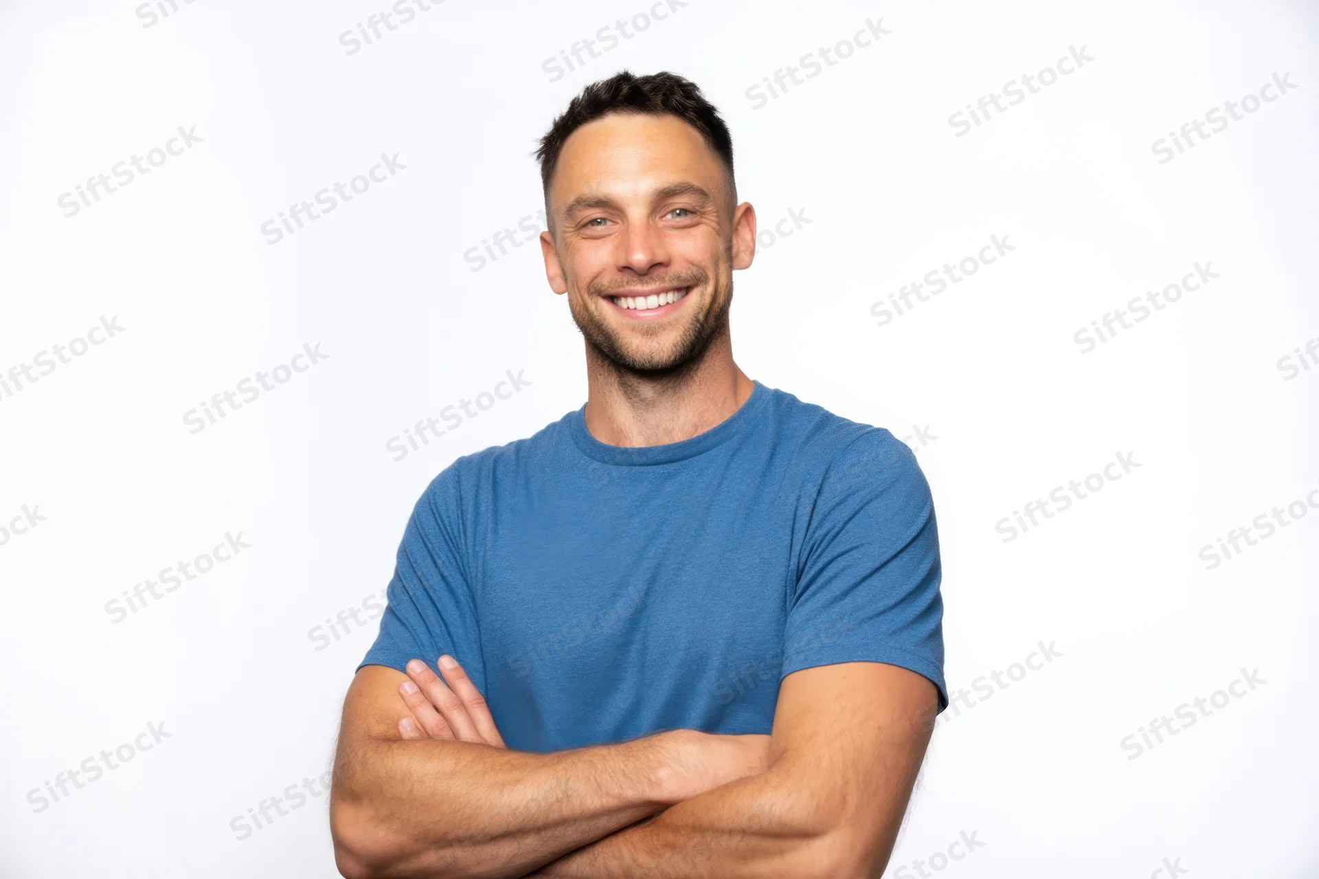 Smiling man with arms crossed wearing blue tshirt against white background