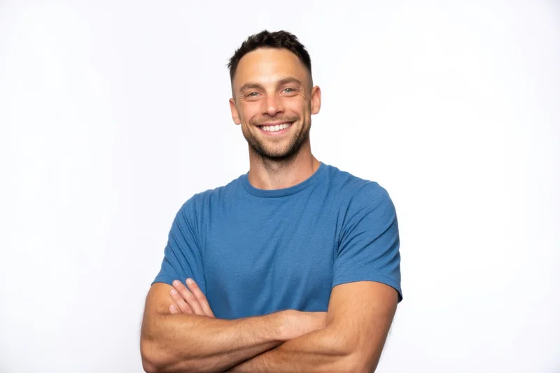 Smiling man with arms crossed wearing blue tshirt against white background