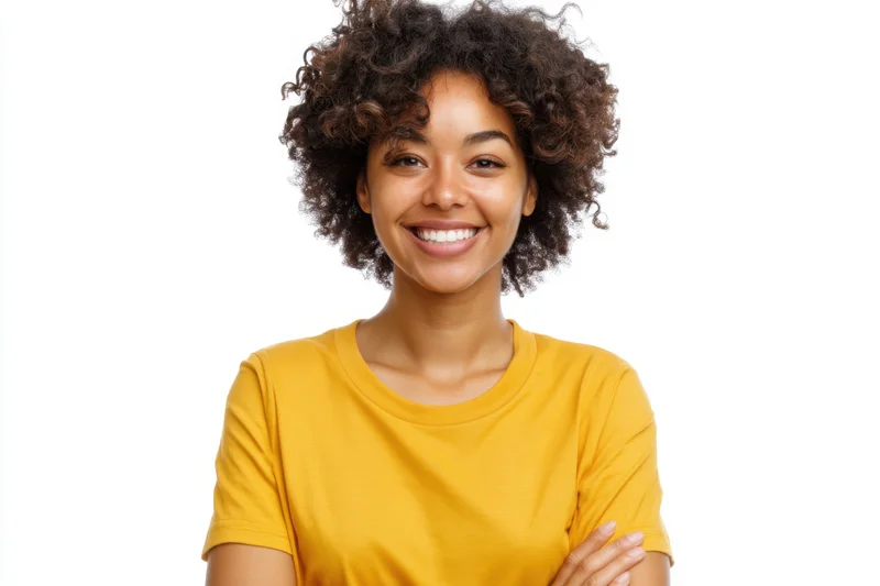 Smiling woman with curly hair wearing yellow tshirt in studio portrait