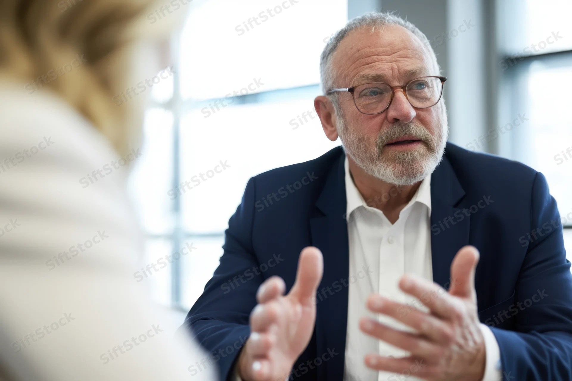 Senior businessman in suit gesturing during office meeting with woman