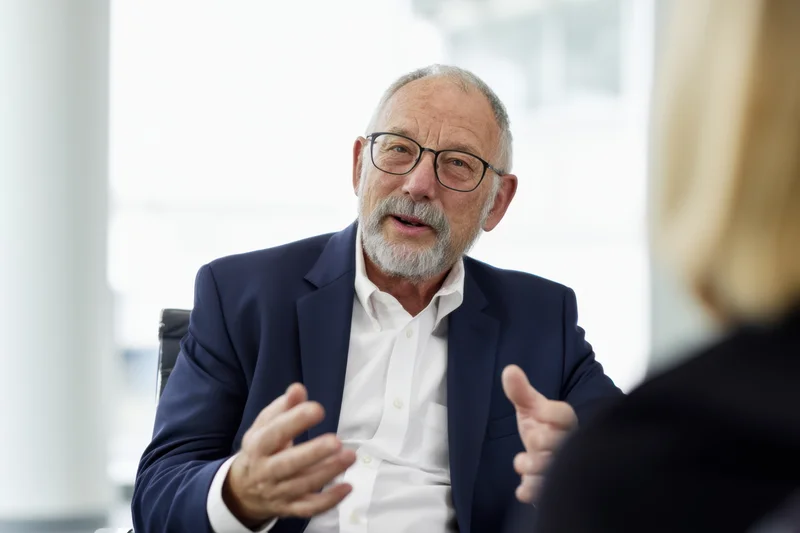 Senior man in suit and glasses talking and gesturing during a business meeting in an office