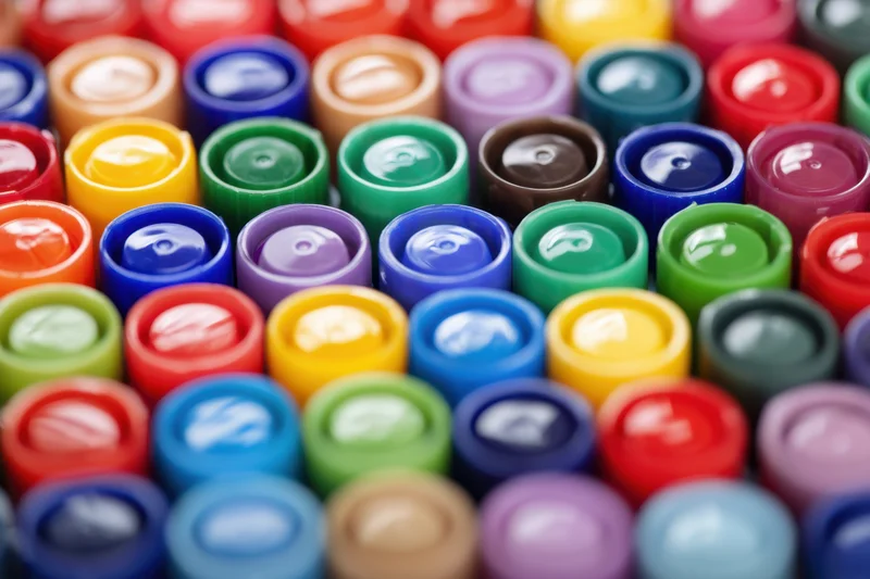 Close-up of colorful marker caps arranged in dense rows, glossy plastic surfaces reflecting light