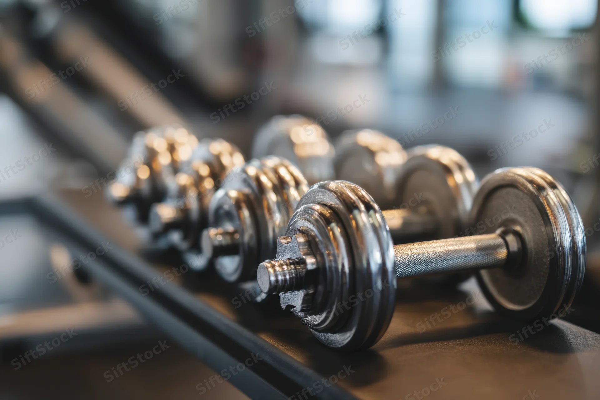 Chrome dumbbells arranged in a row on a gym rack