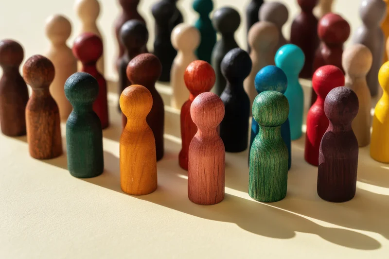Colorful wooden figurines arranged in rows on a neutral surface