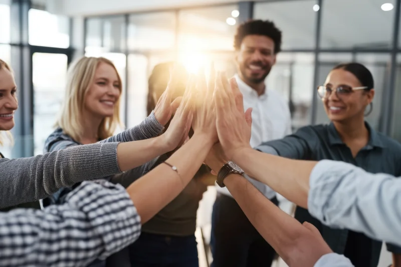 Diverse coworkers giving high-five in modern office interior