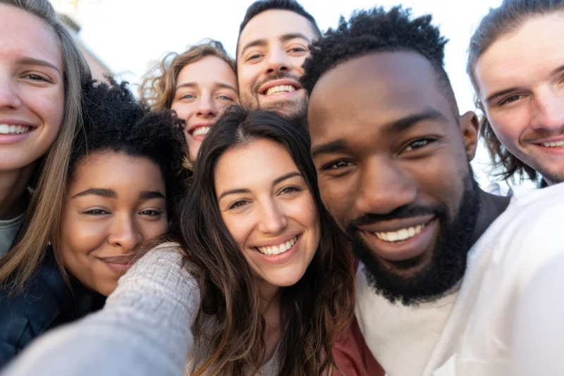 Diverse group of young friends smiling together in a selfie outdoors