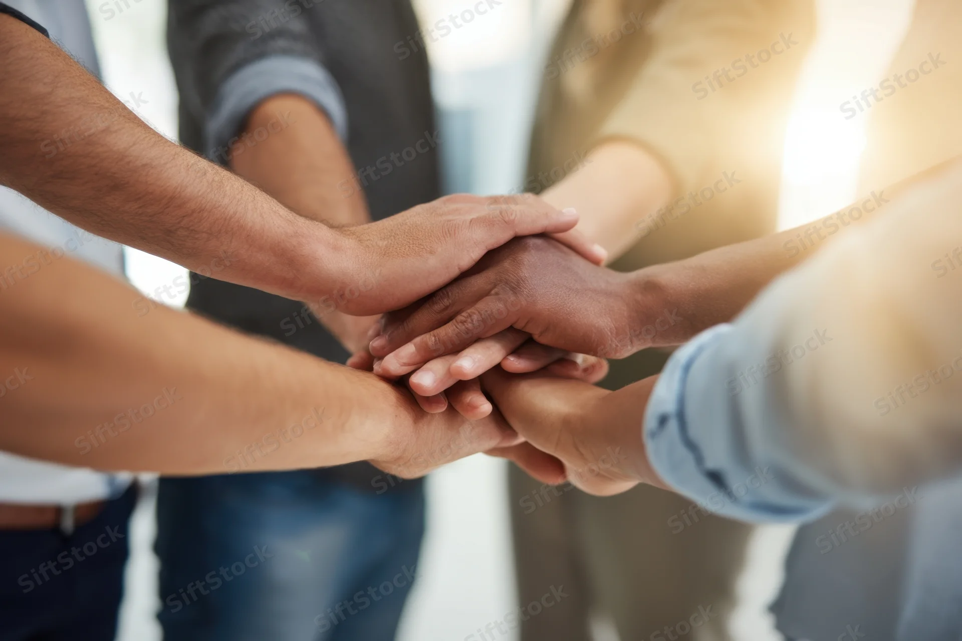 Diverse hands stacked together in a circle symbolizing teamwork and unity in a professional setting