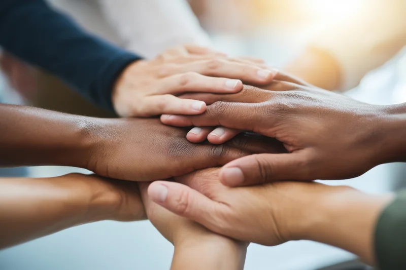 Diverse hands stacked in a circle symbolizing unity and teamwork