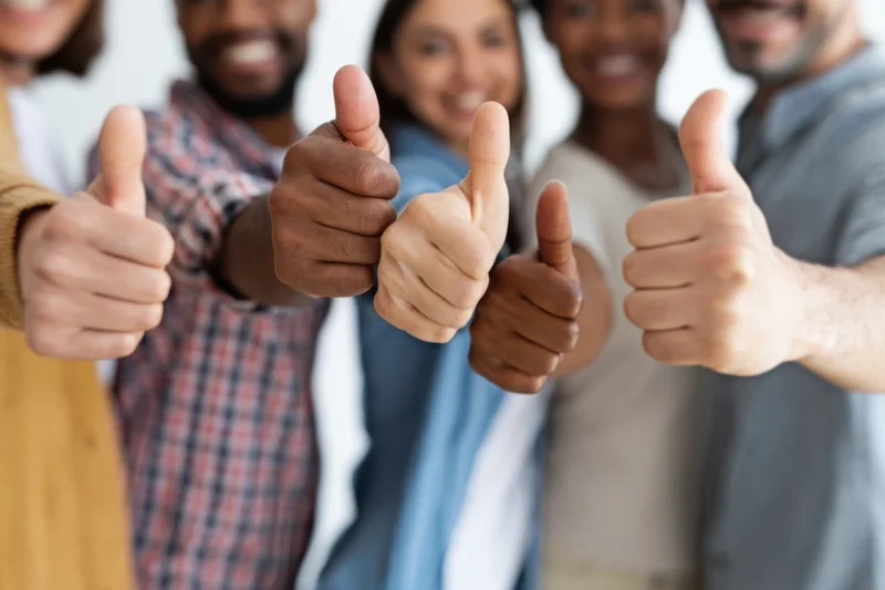 Diverse group of people giving thumbs up in a row close-up