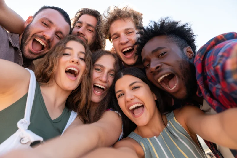 Diverse young friends taking a close-up group selfie outdoors smiling and laughing