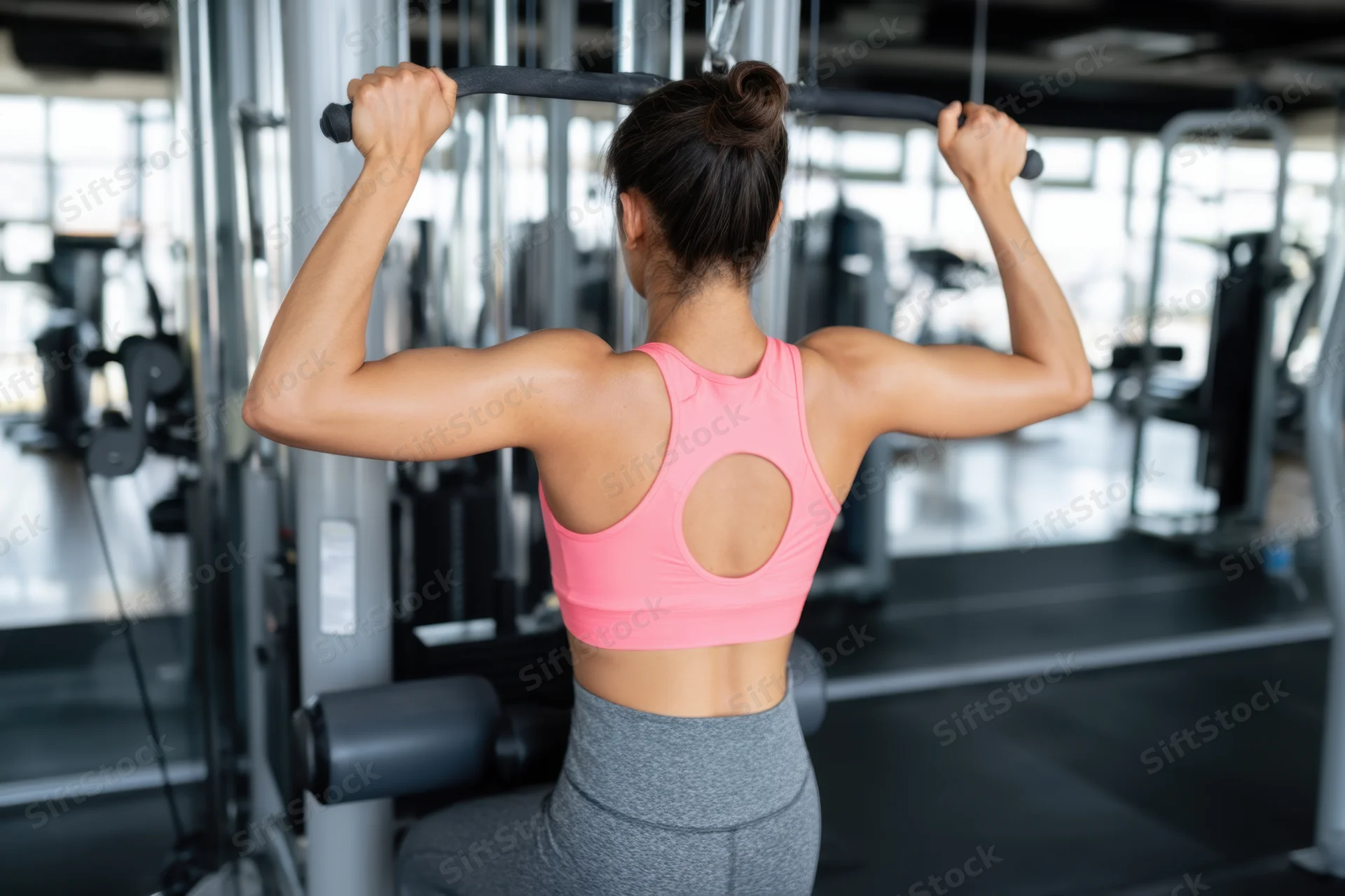 Woman performing back exercise on cable machine in gym