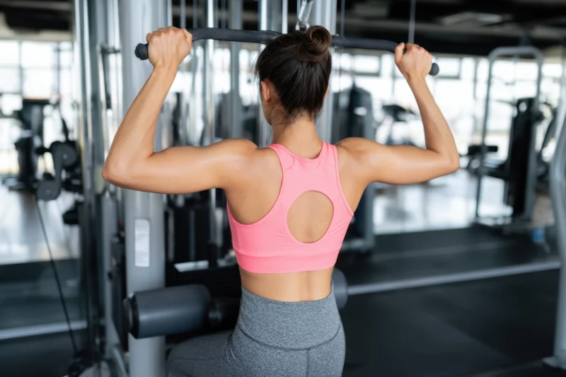 Woman performing back exercise on cable machine in gym