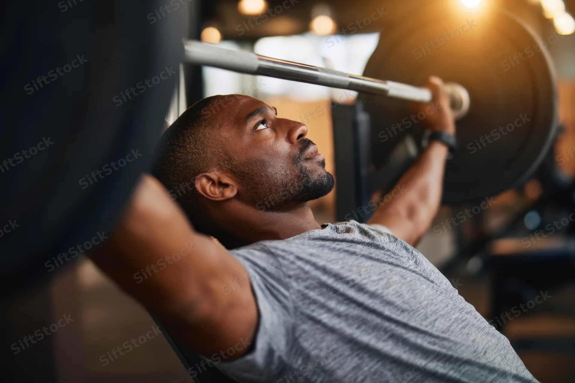 Man performing bench press with barbell in gym