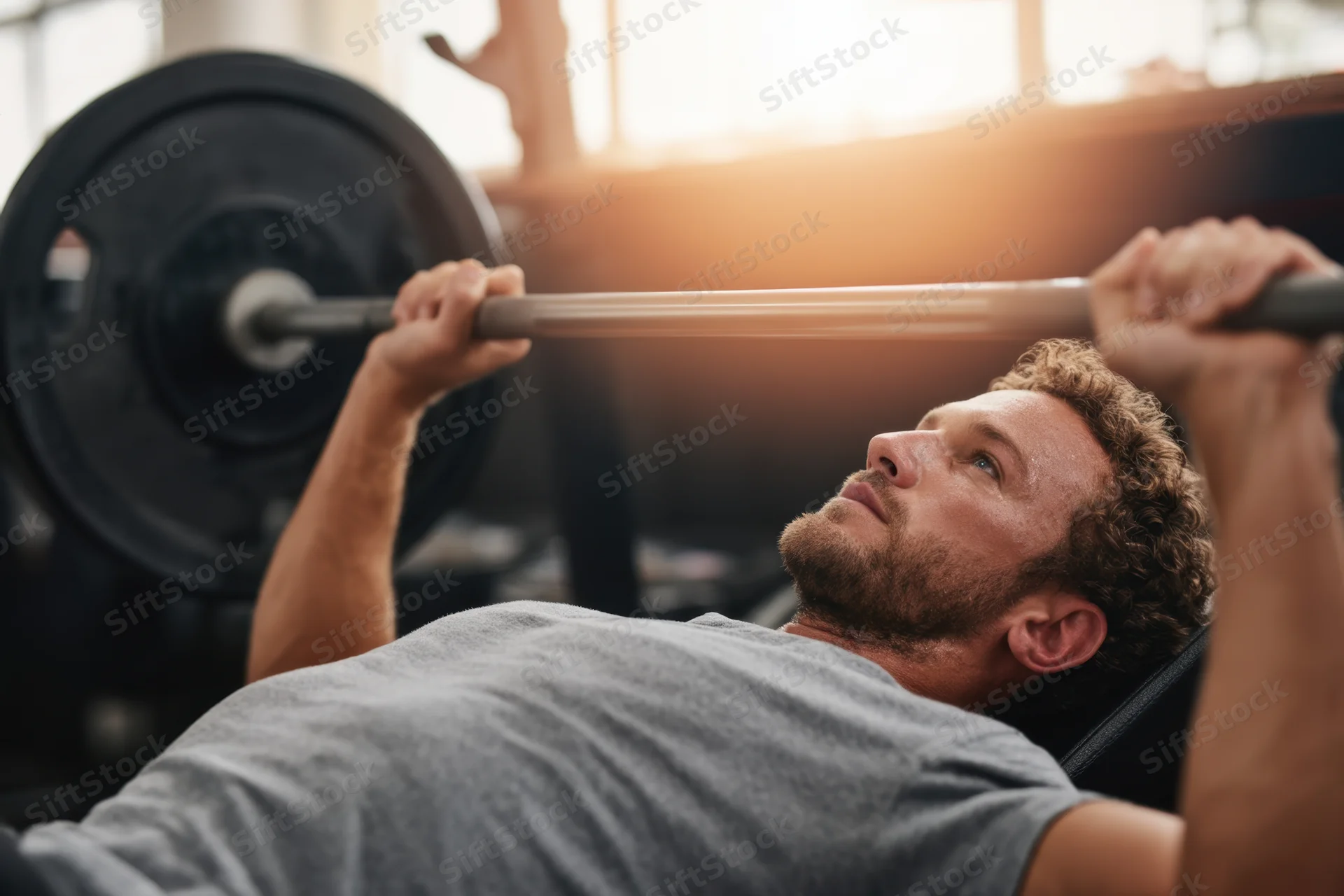 Man performing bench press with barbell in gym