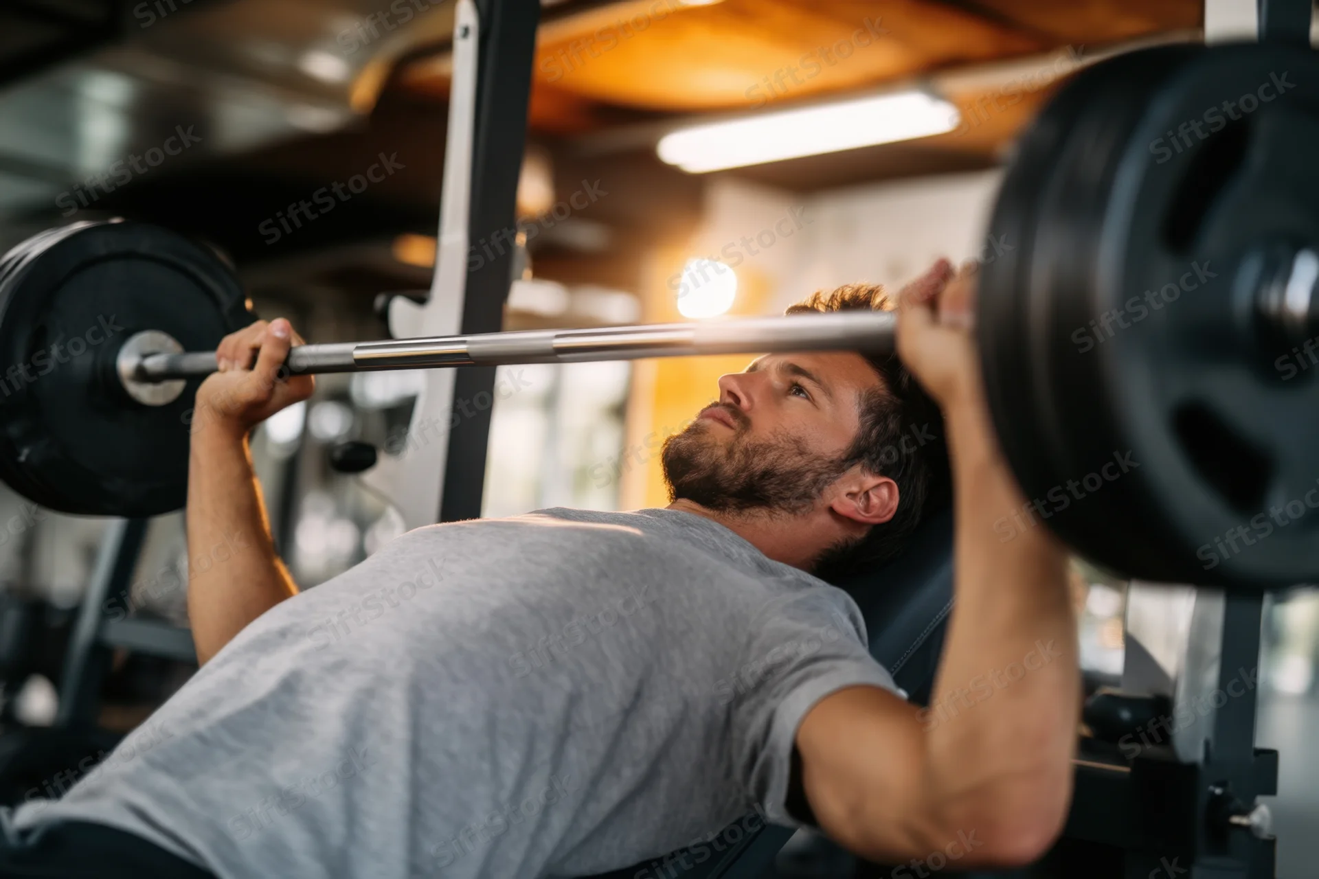 Man performing bench press with barbell in gym