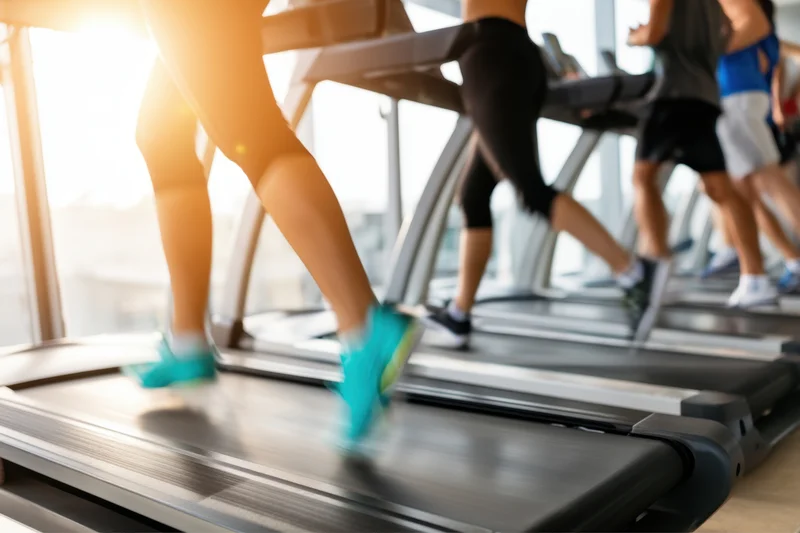 People running on treadmills in a bright modern gym
