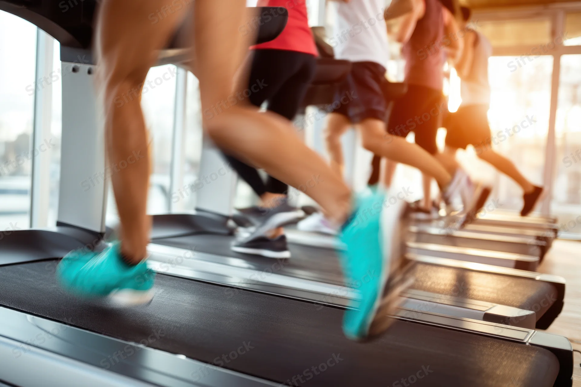 People running on treadmills in a bright modern gym