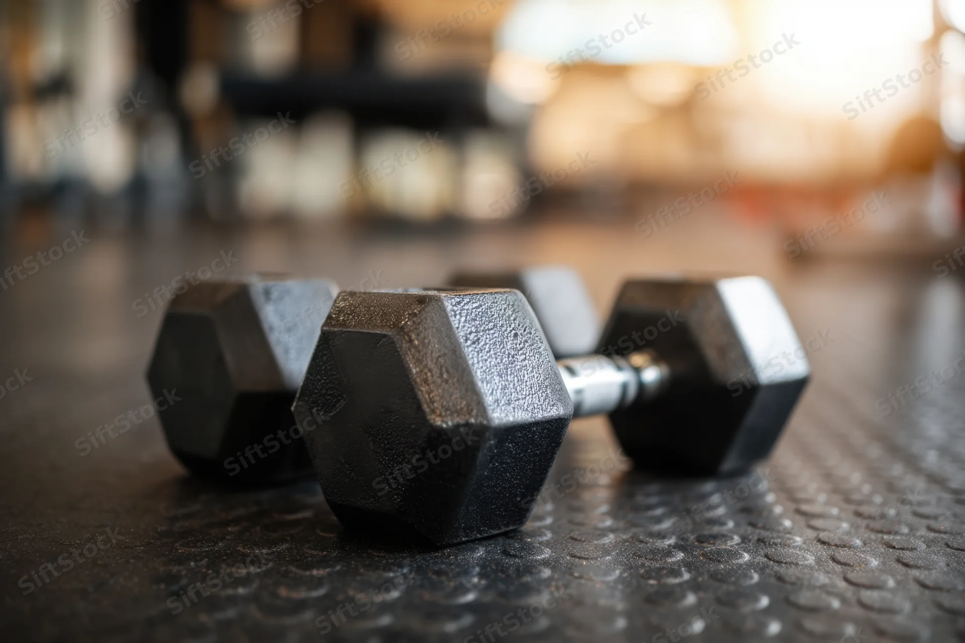 Hexagonal dumbbells resting on textured black gym floor
