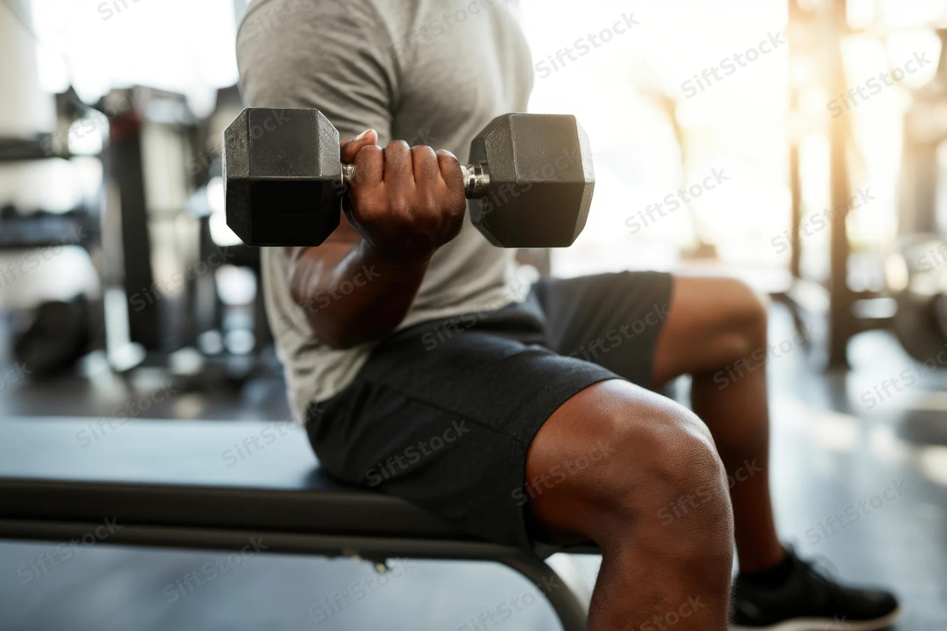 Man performing seated dumbbell curl on gym bench