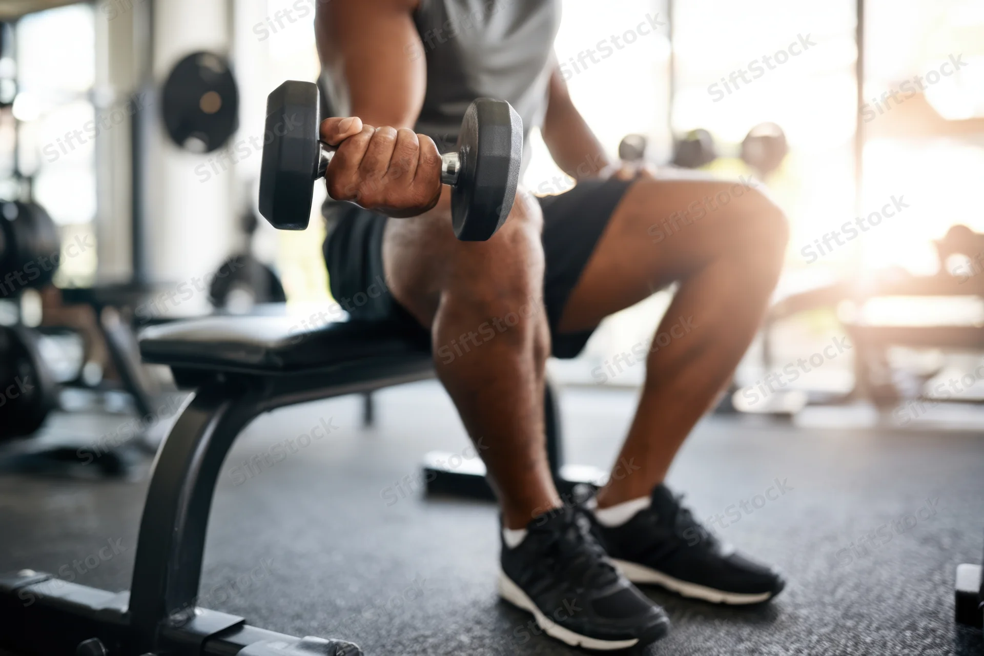 Man seated on gym bench lifting dumbbell during workout